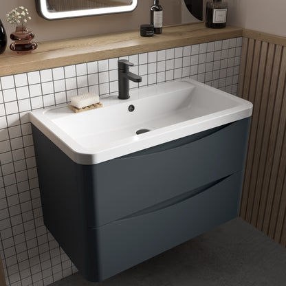 A gray wall-hung bathroom vanity unit with two drawers and a ceramic basin sink, mounted on a wall with white tiles and wooden accents.