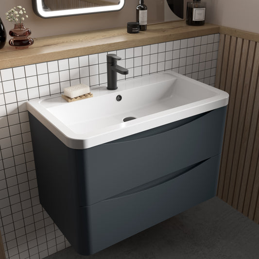 A gray wall-hung bathroom vanity unit with two drawers and a ceramic basin sink, mounted on a wall with white tiles and wooden accents.