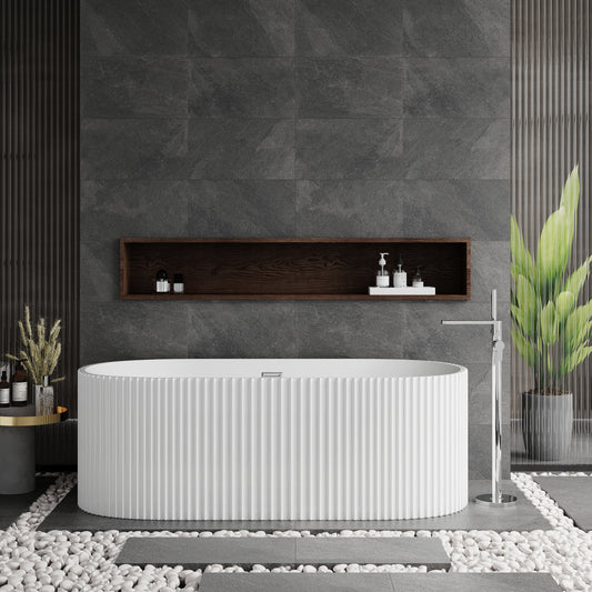 A freestanding white oval bathtub with a fluted design, situated in a bathroom with dark gray walls and a central shelf above the tub featuring toiletries.